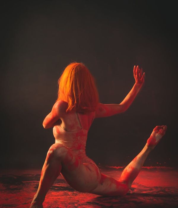 Woman performing a fluid yoga pose in a calm dark environment.